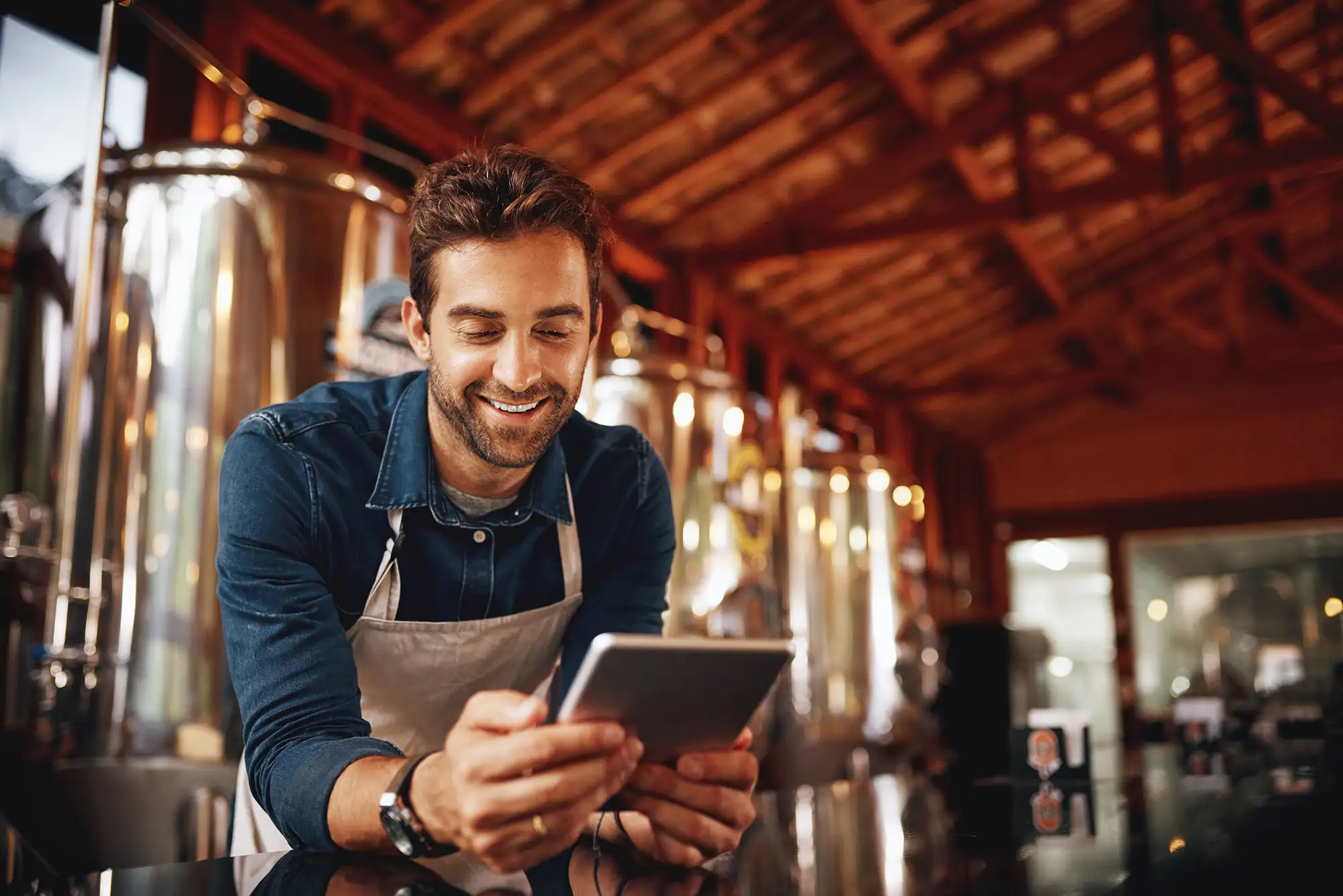 Brewery owner smiles, looks at phone